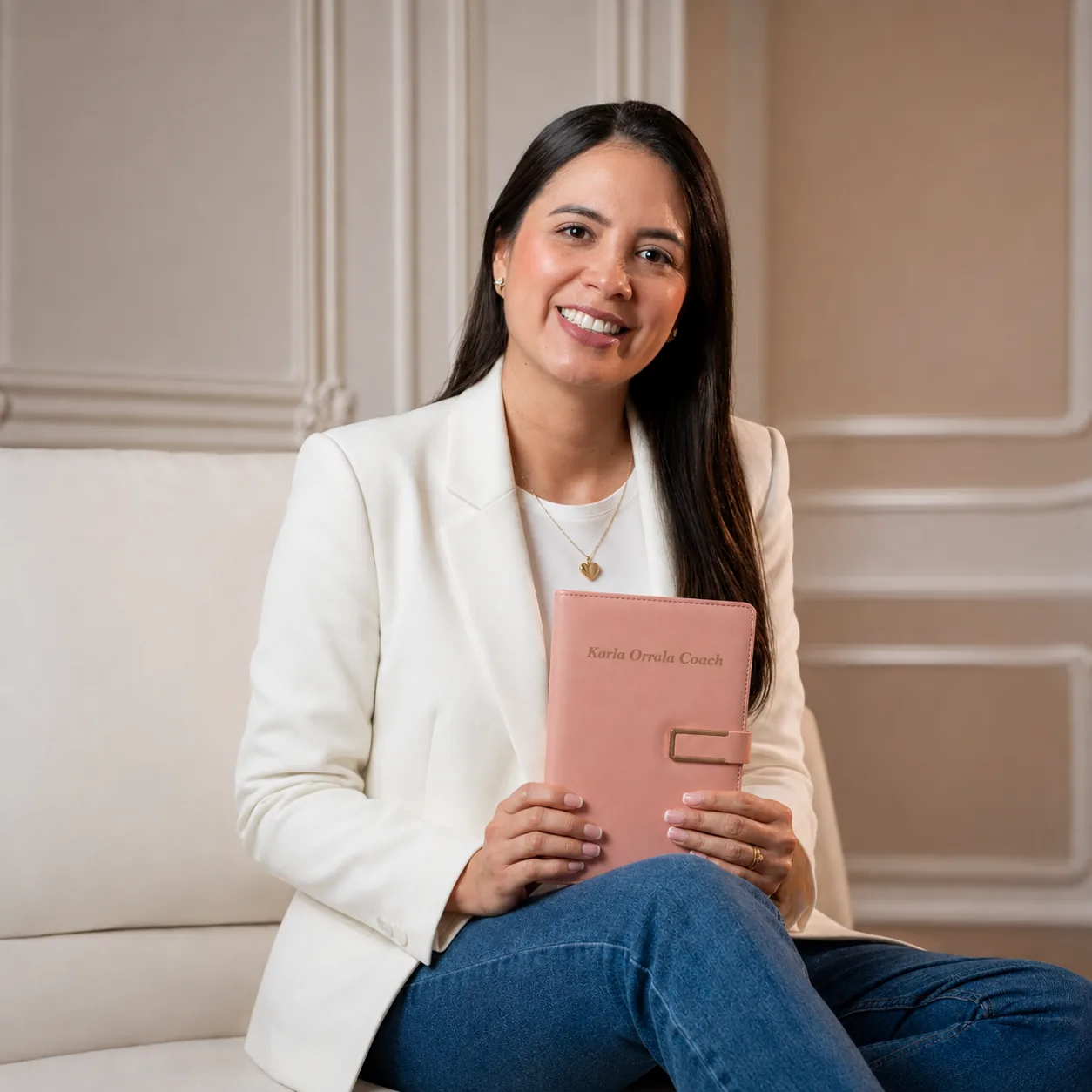 Karla Orrala, coach ontológica, sentada con un libro en un espacio cálido y luminoso